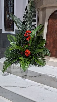 a potted plant with red flowers and green leaves on the top of some steps