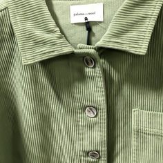 a close up of a green shirt with buttons on the chest and collar, which has a name tag attached to it