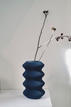 a blue vase sitting on top of a white table next to a plant in it