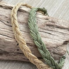 two braided bracelets sitting on top of a piece of wood