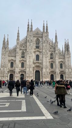 people are walking around in front of a cathedral