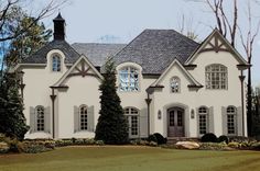 a large white house with lots of windows and bushes in front of the door area