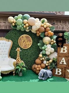 a baby shower is set up with balloons and jungle animals, including an elephant, giraffe, zebra, and balloon arch