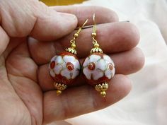 (Internal #EE602-4)  You are bidding on this pair of one bead, 20 mm round RED with pink white flowers CLOISONNÉ bead DANGLE EARRINGS with gold tone filigree caps and bead accents, on gold tone French wire earrings.  This is exactly the pair of earrings you will get.   CLOISONNÉ EARRINGS, CHINA:  Here's how a cloisonné bead is made: A copper body is hammered and welded.  Then wire "cells" (where the word "cloisonné" came from) are formed and soldered on the copper body.  Preliminary enamel filli Pink Round Jewelry With Bead Caps, Round Beaded Earrings With Bead Caps As Gift, Round Beaded Earrings With Bead Caps For Gifts, Elegant Round Earrings With Bead Caps, Handmade Rose Gold Earrings With Round Beads, Nickel-free Round Pink Flower Earrings, Round Pink Nickel-free Flower Earrings, Gold Round Beads Flower Earrings As Gift, Traditional Pink Jewelry With Ear Wire