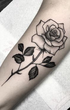 a black and white rose tattoo on the left arm with words written in red ink