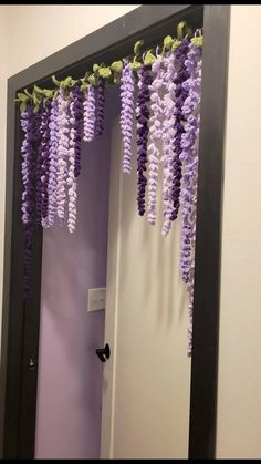 purple flowers hanging from the ceiling in front of a mirror