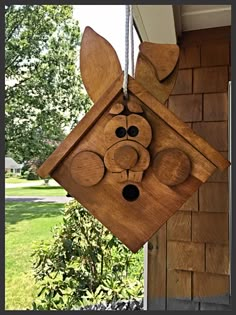 a wooden cuckoo clock hanging from the side of a brick building with trees in the background