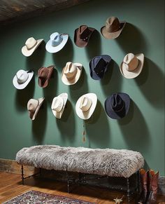 several hats are hanging on the wall above a bench in front of a large rug