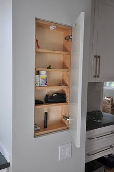 a kitchen with white cabinets and black counter tops in the corner, is seen through an open cabinet door