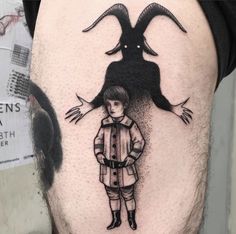 a man's thigh with a drawing of a boy and a demon on it