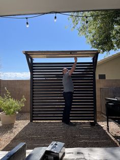 a man standing in front of a metal gate with his hand up to the sky