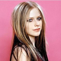 a woman with long hair standing in front of a pink wall