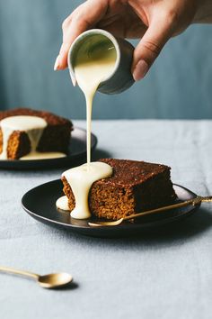 someone pouring white sauce onto a piece of cake