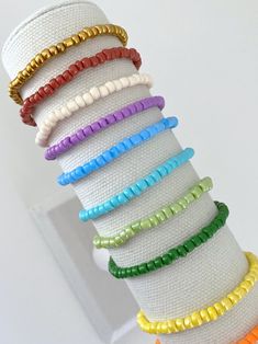 a stack of bracelets sitting on top of a white cloth covered table next to a wall