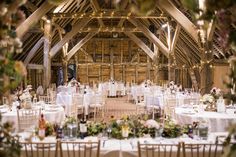 the inside of a barn with tables and chairs set up for a formal function or wedding