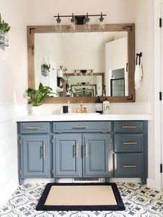 a bathroom with a large mirror and blue cabinetry in the center, along with a rug on the floor