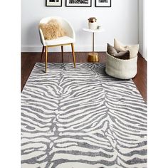 a white and gray rug with zebra print on the floor next to a chair in front of three framed pictures