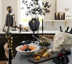 a table topped with halloween food next to a skeleton statue