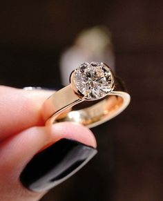 a close up of a person's hand holding a ring with a diamond on it