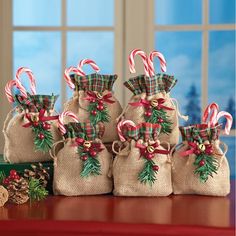 three bags filled with candy canes sitting on top of a table next to christmas decorations