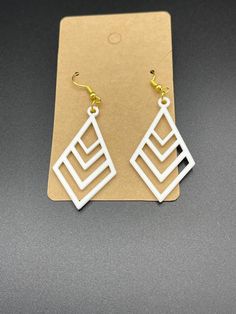 the earrings are made from white plastic and have square shapes with gold accents on them