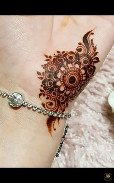 a henna tattoo on someone's hand with brown and white flowers in the background