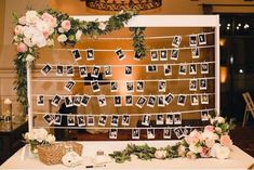 a table topped with pictures and flowers next to a wall hanging from the side of it