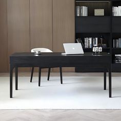 a desk with a laptop on it in front of a bookcase and bookshelf