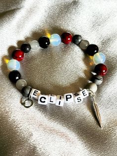 a beaded bracelet with the word eclipse spelled on it and a pair of scissors