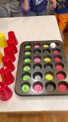 two children standing in front of a muffin tray with cupcakes on it