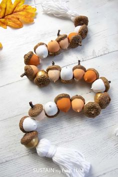 the beaded bracelets are made out of acorns and other beads on a white wooden surface