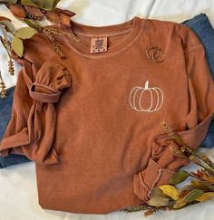 It's that time of year, you know what time...Pumpkin Time!  The days become shorter but they sure seem to slow down.  Our simple pumpkin outline tee is the perfect way to show you love the season in perfect minimalist style.   The softest and most cozy Comfort Colors tee with a cute fall style!  Pair with your favorite jeans, or size up one and grab your comfy leggings!  You are choosing Long Sleeve or Short Sleeve Shown here in the long sleeve option with cream thread.  If you prefer a differen Fall Shirts Simple, Pumpkin Patch T Shirts, Fall And Halloween Shirt Ideas, Fall Embroidery Shirts, White Embroidered T-shirt For Fall, Long Sleeve T-shirt With Embroidered Graphics For Fall, Thanksgiving Graphic Tees, Casual Embroidered Fall T-shirt, Orange Crew Neck T-shirt For Fall