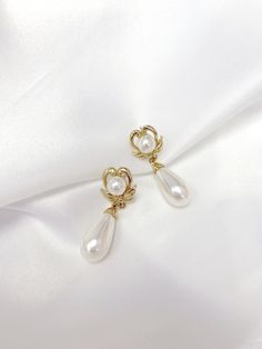 Vintage Inspired Earrings from the 1950s & 1960s. This beautiful Vintage Faux Pearl Classic Heart-Wing Drop Earrings are plated in Champagne Gold tone metal leading to a Classic style elongated white faux pearl tear drop. Earrings will be provided with Gold plated Butterfly backs. Items will be wrapped in a beautiful gift box.  Go Social : FOLLOW US ON INSTAGRAM : @RAQUEL.VINTAGE Gold Heart Shaped Clip-on Earrings For Wedding, Elegant Gold Heart-shaped Clip-on Earrings, Elegant Gold Heart Shaped Clip-on Earrings, Classic Gold Heart Earrings For Formal Occasions, Elegant Heart-shaped Pearl Earrings For Party, Elegant Heart-shaped Clip-on Jewelry, Vintage Yellow Gold Clip-on Earrings For Party, Vintage Gold Pearl Earrings As Gift, Vintage Gold Pearl Earrings For Gift