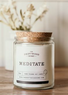 a white candle sitting on top of a wooden table next to a vase with flowers