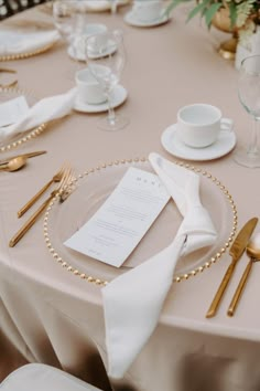 the table is set with gold and white place settings, silverware, and napkins