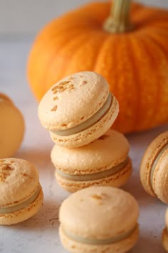 a pile of macaroons sitting on top of a table next to an orange pumpkin