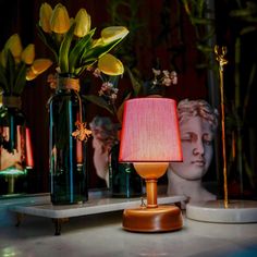 a table topped with vases filled with flowers next to a lamp on top of a table