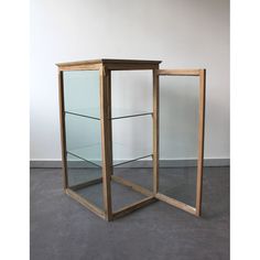 a wooden and glass display case on the floor in front of a wall with white walls