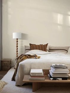 a bed sitting in a bedroom next to a table with books on top of it