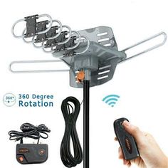 a hand holding a remote control next to a tv antenna with multiple antennas on it