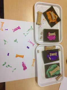 two trays filled with dog treats on top of a wooden table next to a white piece of paper