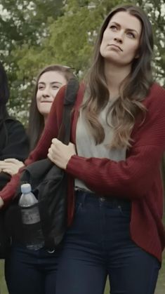 three young women are standing together in the park