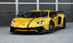 a yellow and black sports car parked in front of a garage door with shutters