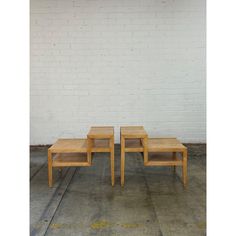 two wooden tables sitting next to each other in front of a white brick wall and concrete floor