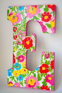 the letter e is decorated with bright flowers and green leaves on it's sides