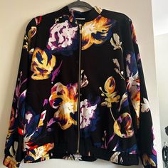 Nwot Beautiful Floral On A Black Background Printed Bomber Style Jacket With A Full Zip Front Features: Bomber Style With An All-Over Floral Print Gold-Tone Zipper Mandarin Style Collar Long Sleeves With Elasticized Cuffs Elasticized Bottom Hem Back Yoke With Pleat Detail 2 Slant Pockets Fit Is Easy Wear But Semi-Fitted Chest 1” Below Armhole Is 46.5” Length Is 24.375 Fabric Is 97% Poly 3% Spandex Machine Washable Trendy Floral Print Outerwear For Work, Floral Print Outerwear For Fall Workwear, Fall Floral Print Outerwear For Work, Black Casual Outerwear With Floral Print, Black Floral Print Casual Outerwear, Black Long Sleeve Outerwear With Floral Print, Casual Black Floral Print Outerwear, Chic Black Floral Print Outerwear, Black Floral Print Long Sleeve Outerwear