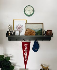 there is a clock on the wall above a shelf with other items and decorations around it