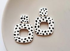 two white and black polka dot earrings on a plate