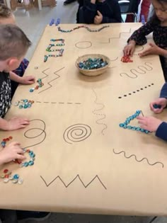 children are playing with beads on a table