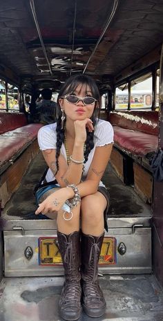 a woman sitting in the back of a truck with her hand on her chin and wearing cowboy boots